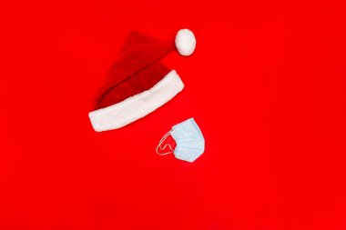 Kırmızı şapkalı ve maskesiz kırmızı arka planda mavi maske takan yassı kadın.,