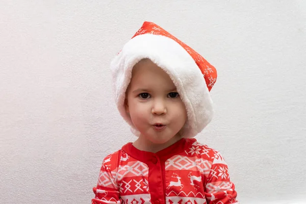 Νήπιο στο κόκκινο καπέλο Σάντα έκπληκτος και ενθουσιασμένος περιμένοντας τα Χριστούγεννα και την Πρωτοχρονιά Royalty Free Φωτογραφίες Αρχείου
