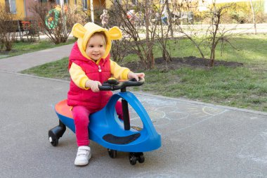 Modern komik gündelik kıyafetleri olan beyaz çocuk salıncaklı araba sürüyor..