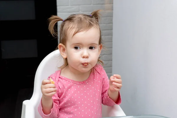 Портрет милого маленького симпатичного белого ребенка, который ест со смешными эмоциями — стоковое фото