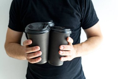 Elinde kahve bardakları olan bir adam..