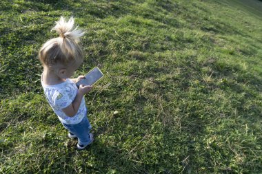 Beyaz saçlı tatlı bir kız oynuyor ya da cep telefonunda siyah ekranla öğreniyor.