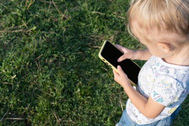 Çocuk cep telefonunda kayıyor, koca parmağıyla.