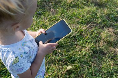 Çocuk ellerinde siyah ekranlı cep telefonuyla yakın plan.