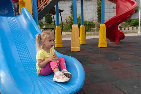 Cute little caucasian child sits on a slide after riding — Stockfoto