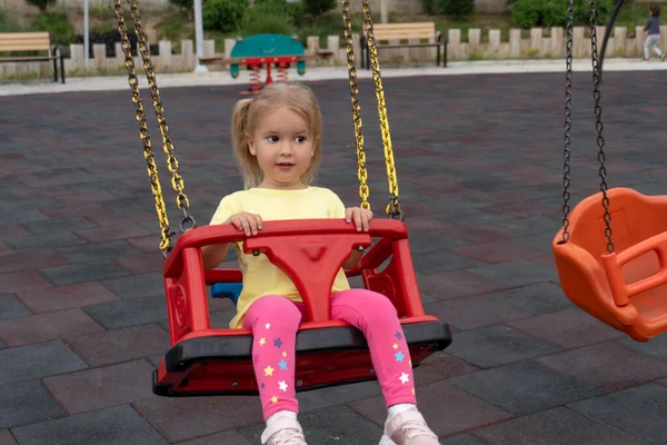 Cute caucasian child swings on swing, with interested and surprised expression. — Φωτογραφία Αρχείου