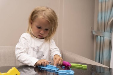 Ağlayan çocuk renkli oyun hamuruyla oynuyor..