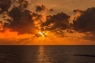Almanya 'da Buesum yakınlarındaki Wadden Denizi üzerinde dramatik gökyüzü ve bulutlarla güzel bir altın gün batımı.