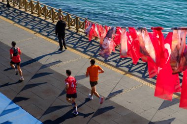 Tekirdağ, Türkiye 30 Ekim 2025: 29 Ekim 'deki Cumhuriyet Günü kutlamaları sonrasında deniz kenarında bir gezinti alanı boyunca insanlar Türk bayrakları altında yürüyor.