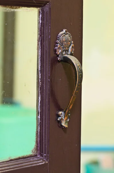 Old brass handle on dark wood door. — Stock Photo, Image