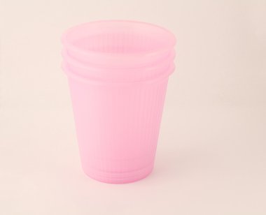 Beyaz arkaplanda izole edilmiş pembe plastik bardak