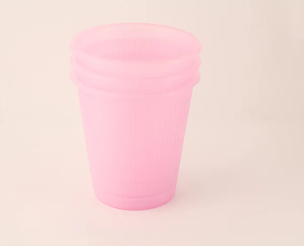 Beyaz arkaplanda izole edilmiş pembe plastik bardak