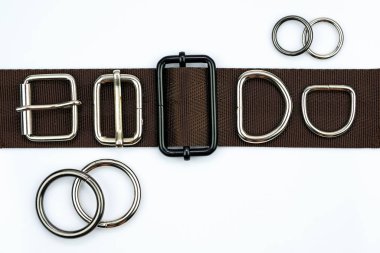 Brown belt with adjusters, buckles, rings, half rings top view. Metal bag accessories on a belt strap on a white background. Attachments for clothes and backpacks. clipart