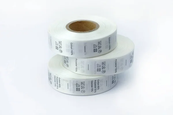 clothing care labels. Clothing labels, sewing accessories. White skeins, a roll of ribbon with information on washing and fabric composition.