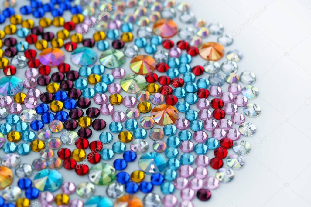 Acrylic stones of different sizes and colors top view. Multi-colored plastic stones for clothes and accessories. Decorative stones in red, yellow, pink and blue.