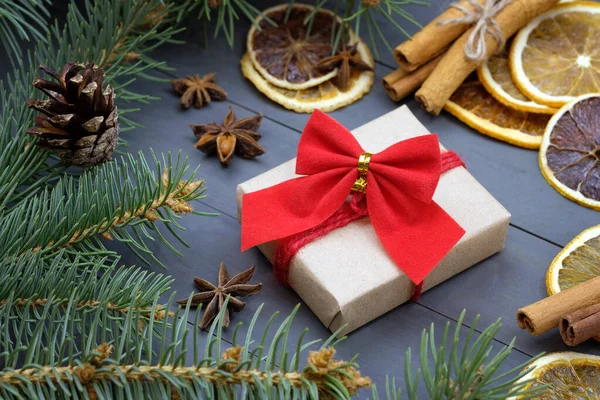 Christmas theme with oranges and cinnamon. Gift box with a red bow on the table with cinnamon sticks, dry oranges and anise. new year composition