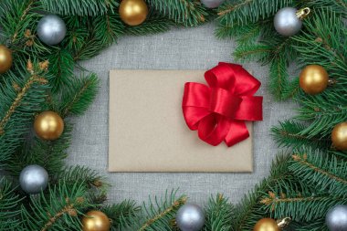 Mutlu yıllar tebrik kartı. Fotokopi alanı ile Noel teması. Gri ve altın renkli neşeli topları olan bir Noel ağacının dalları. Kırmızı pruva görünümlü zarf. 