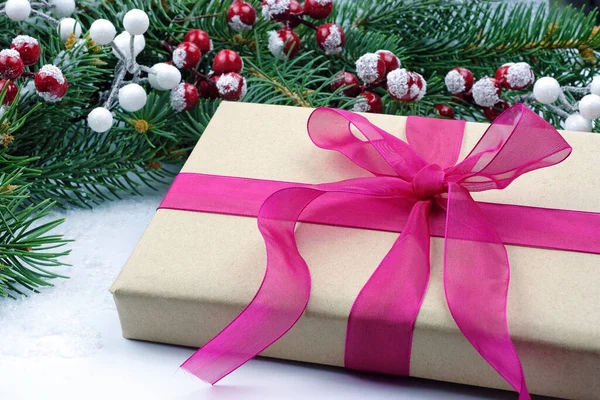 クリスマスや新年のリボンをプレゼント クリスマスツリーの枝や赤い果実の背景にピンクの弓を持つボックス 新年のテーマ 新年への贈り物 — ストック写真