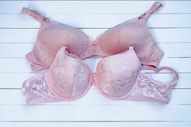 Beyaz arka plan manzaralı iki pembe sutyen. Dantelli pembe iç çamaşırı. Tahtalardan yapılmış sütyen ve fincanlar.. 