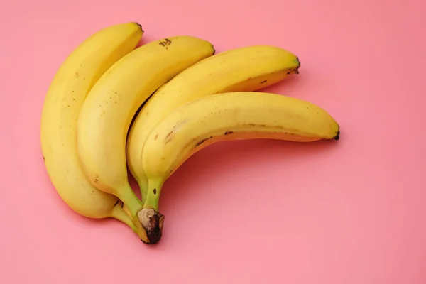 A bunch of bananas on a pink background top view. Ripe bananas with copy space.