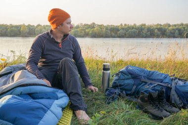 Genç turist doğada uyku tulumunda dinleniyor. Uyku tulumu çimenlerin üzerinde yatıyor.