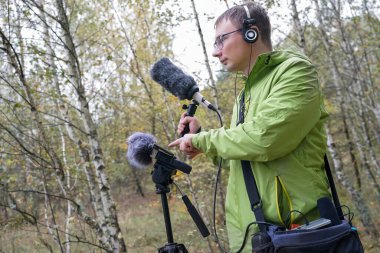 Kulaklığı ve kulaklığı olan adam doğanın seslerini kaydediyor. Ortam Sesleri Kaydediliyor