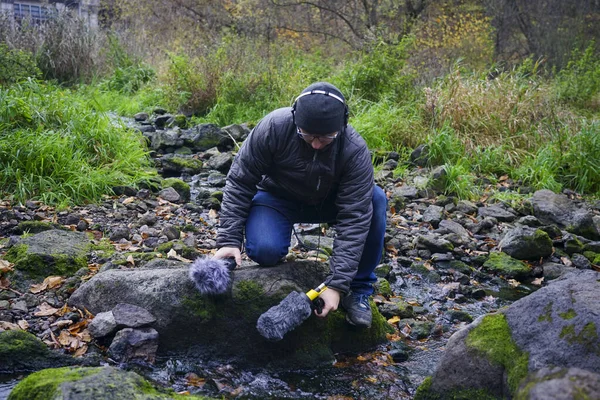 The guy is holding a microphone gun in his hand. Recording nature sounds. Hand holds a microphone gun to record sounds of nature. Sound technician records sounds of nature. Recording Ambient Sounds