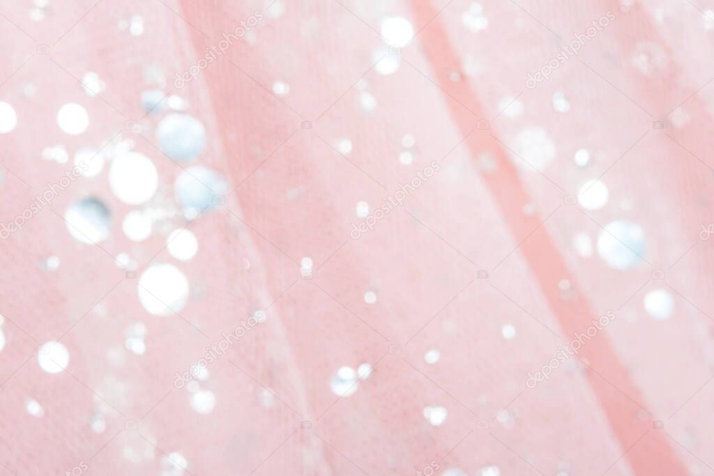 Pink tulle fabric with sequins as background and texture, close-up.