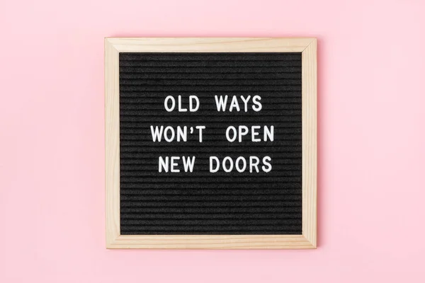 Old Ways Won't Open New Doors. Motivational quote on black letter board on pink background. Concept inspirational quote of the day. Greeting card, postcard.
