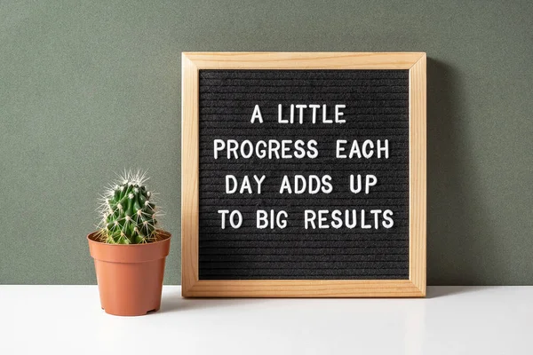 A little progress each day adds up to big results. Motivational quote on letter board, cactus, succulent flower on white table. Concept inspirational quote of the day. Front view.