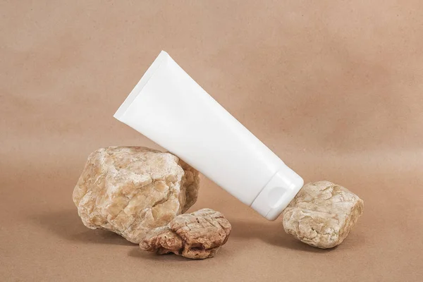 White blank cosmetic tube with cream, moisturizing lotion or shampoo background on beige craft paper background. Natural Organic Spa Cosmetic concept Front view.
