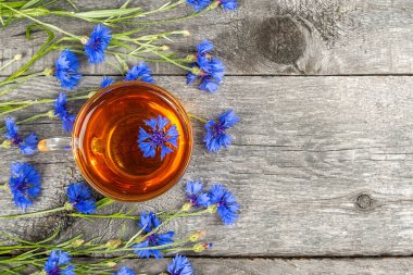 Bir fincan bitki çayı ve ahşap arka planda mavi çiçek. Üst Görünüm Düz yatay Boşluğu Kopyala