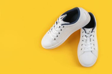 Beyaz spor ayakkabıları, sarı arka planda ayakkabı bağcığı olan spor ayakkabıları. Spor yaşam tarzı konsepti Üst Görünüm Düz Kopya Alanı.
