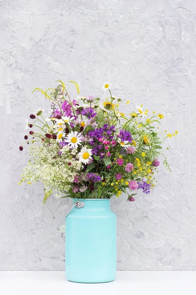 Bouquet of bright wild flowers in tin can vase on background gray stone wall. Template for postcard. Concept Women\'s day, Mothers Day, Hello summer or Hello spring.