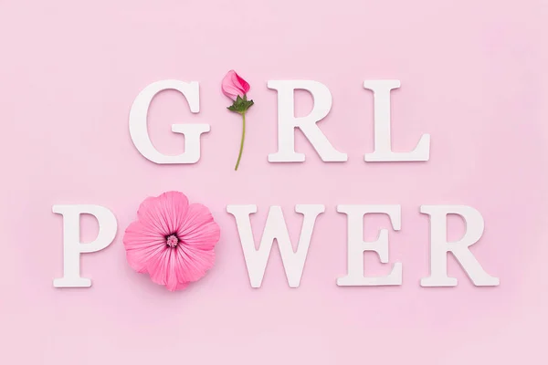 Girl power. Motivational quote from white letters and beauty natural flowers on pink background. Women,power creative concept.