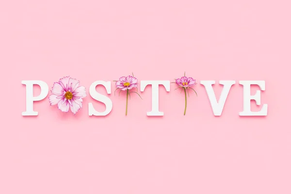 ポジティブだ ピンクの背景に白い文字と美しい自然の花からのモチベーションの引用 その日の創造的な概念のインスピレーションの引用 — ストック写真