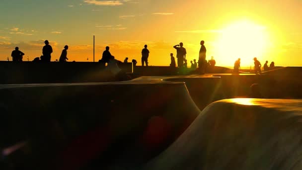 Lidé skateboardingu v slavné Santa Monika skatepark při západu slunce. — Stock video