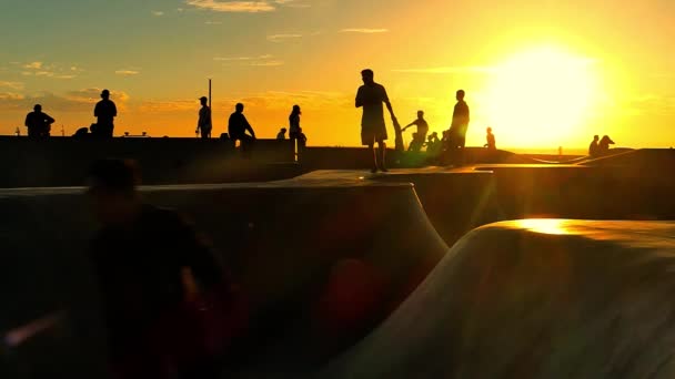 Lo skateboard delle persone nel famoso skatepark di Santa Monika al tramonto . — Video Stock