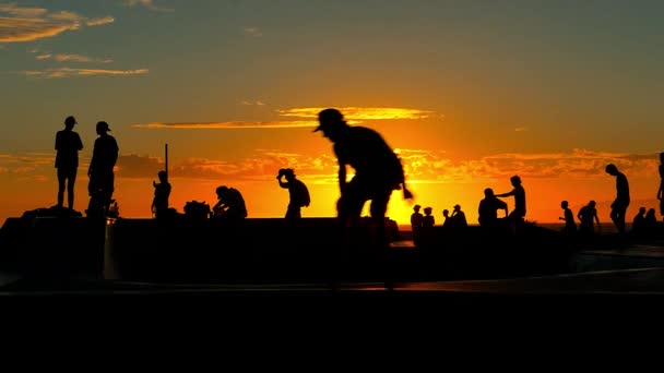 Lidé skateboardingu v slavné Santa Monika skatepark při západu slunce. — Stock video
