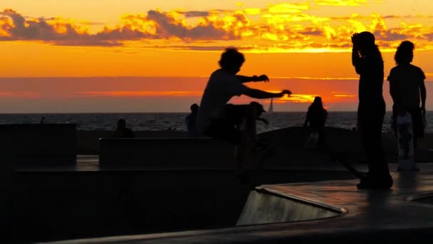 Pessoas de skate no famoso parque de skate Santa Monika ao pôr do sol . — Vídeo de Stock