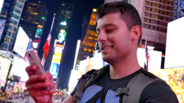 Usmívající se mladý muž, textové zprávy na Times Square — Stock video