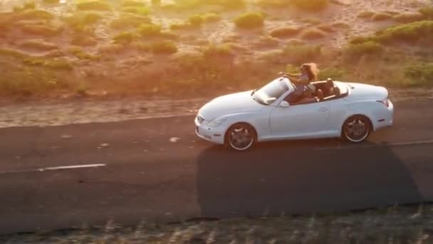 Junges Paar fährt Cabrio-Auto bei Sonnenuntergang am Strand Antenne fliegen durch Sommer Abenteuer Sonnenschein Glück — Stockvideo