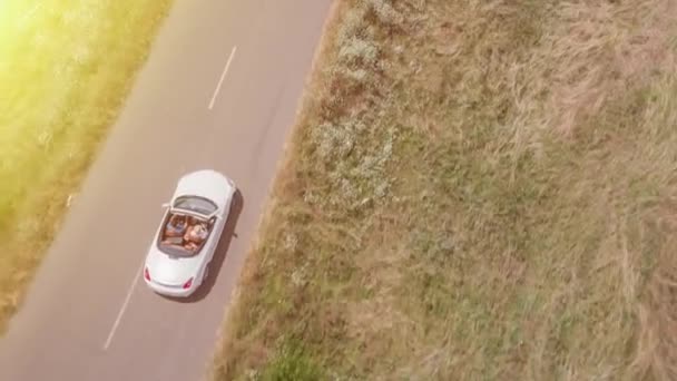 Vuelo aéreo sobre coche convertible que conduce por la carretera del campo al atardecer Concepto de aventura de viaje — Vídeos de Stock