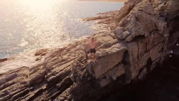 Jeune homme athlétique debout sur le bord de la falaise avant de sauter au coucher du soleil Sports extrêmes Vacances Adrénaline Succès Vacances Belle île Emplacement Plage Océan Concept — Video