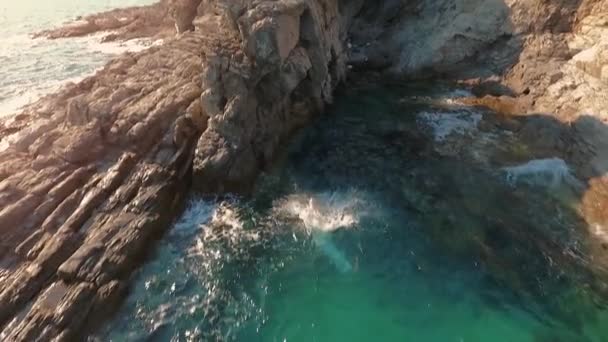 Молодой спортсмен, прыгающий с морской скалы, плескающийся в воду в медленном движении — стоковое видео