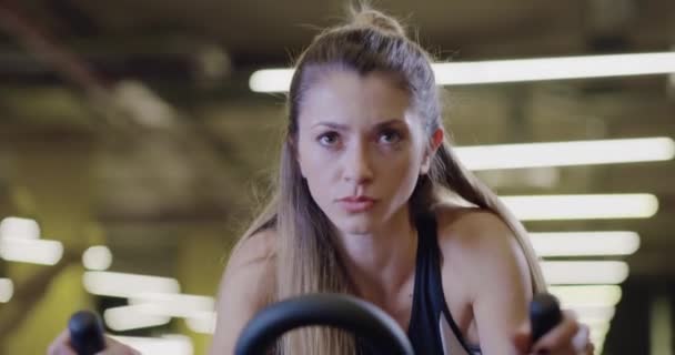 Сильная красивая женщина крупным планом фитнес-тренировки на стационарных велосипедах в помещении Фитнес кардио тренировки мотивация здоровья Фокусное фитнес-концепция 4k — стоковое видео