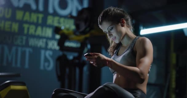 Passform Sportig kvinna tar en paus efter träningen Använda telefon inomhus Aktiv livsstil Fritid Fitness Technology Concept 4k — Stockvideo