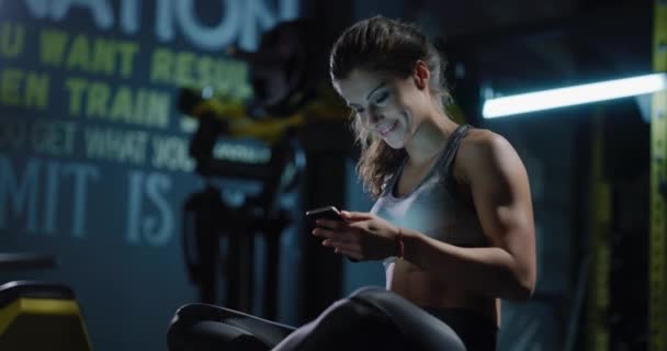 Спортсменка держит в руках смартфон, на котором изображена технология здорового образа жизни 4k — стоковое видео