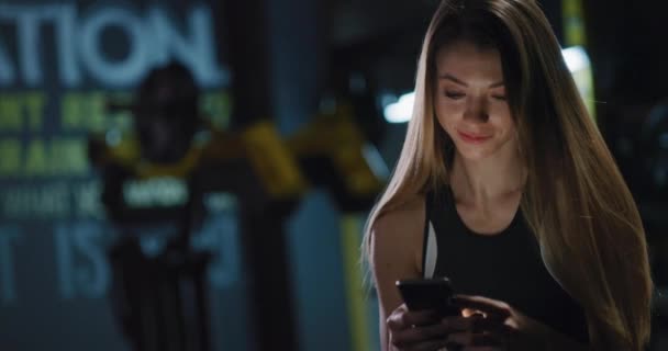 Vacker atletisk kvinna Att ha en paus Kontrollera sociala nätverk Närbild Inomhus Aktiv livsstil Fritid Fitness Technology Concept 4k — Stockvideo