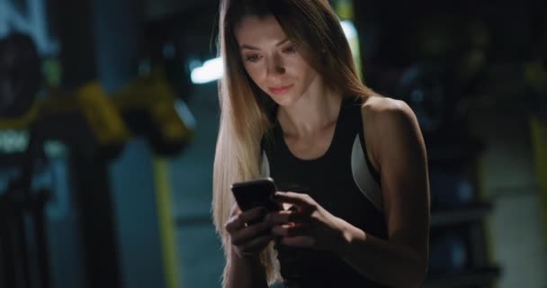 Joven Fit Mujer En Ropa Deportiva Tener un descanso Comprobación de Redes Sociales Primer plano Fitness Center Vida Saludable Relajación Fitness Technology Concepto 4k — Vídeo de stock